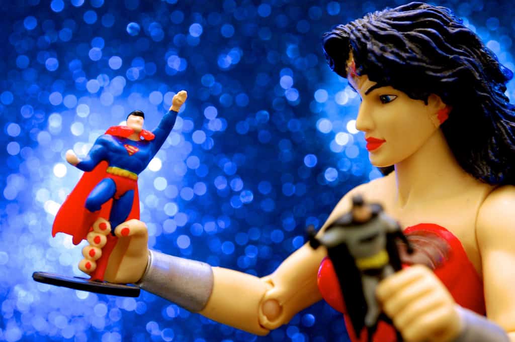 Photograph of a Wonder Woman toy playing with smaller figures of Batman and Superman.